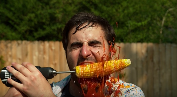 Video de hombre comiendo mazorca con taladro en cámara lenta slow motion